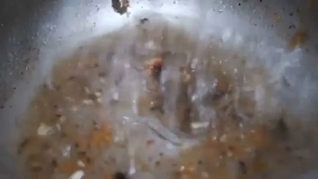 Inside view from a drain camera showing a pipe lined with brown debris and a small stream of water